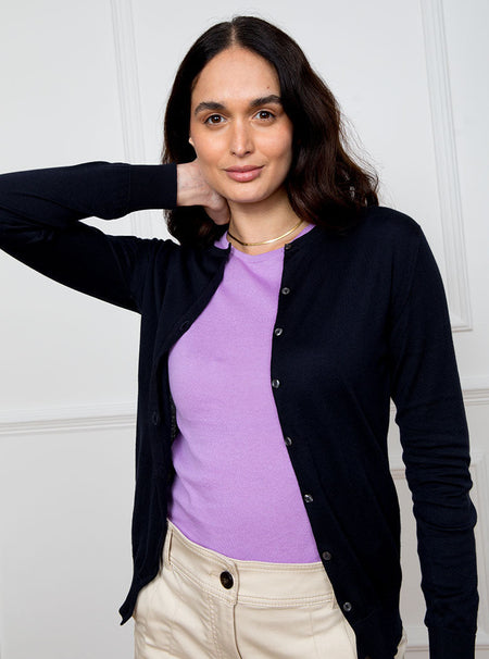 Woman wearing navy blue long sleeve cardigan knit in a luxury and premium sea island cotton. Paired with ultraviolet/lilac short sleeve knit top.